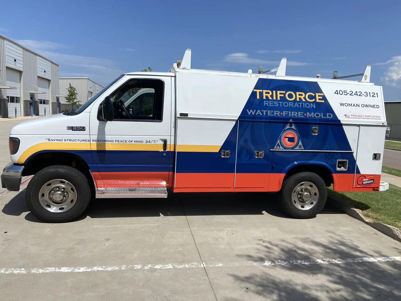 Driver side of the Triforce Restoration E-350 showing yellow, blue, and orange retro striping from the front bumper to the service body