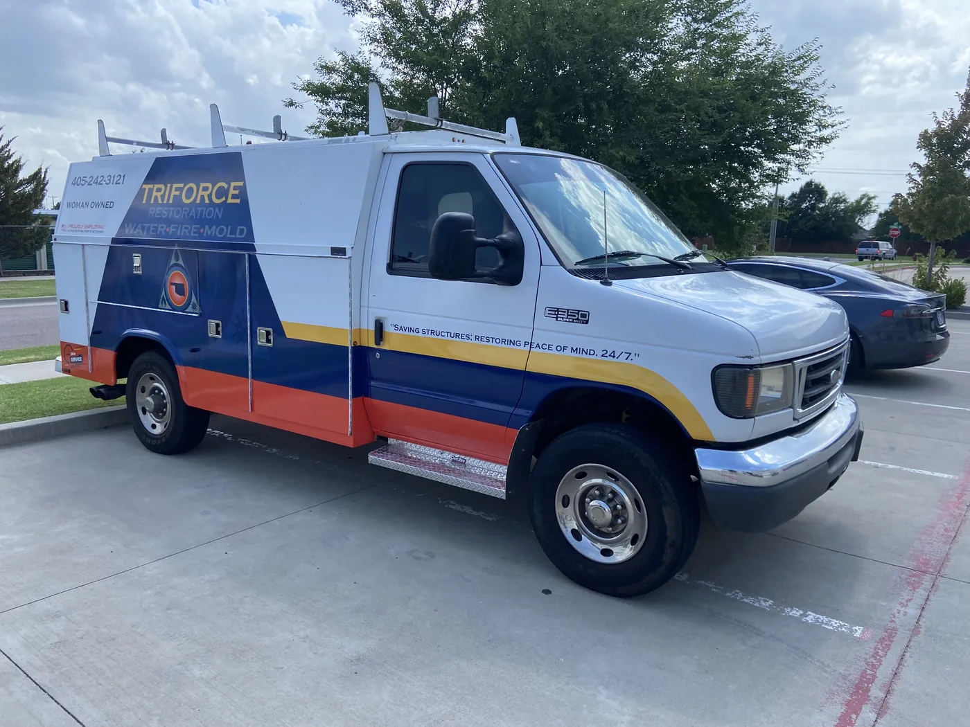 Front three-quarter view of the Triforce Restoration truck with the tagline on the cab door and striping along the body